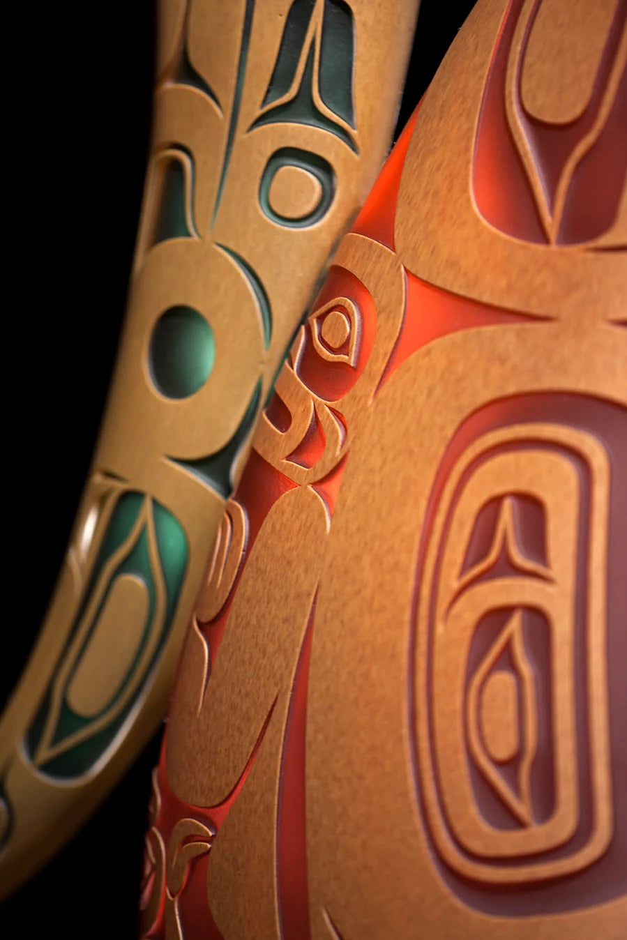 Blown glass sculpture by Preston Singletary featuring Northwest Coast formline design in warm amber and red with green accents.