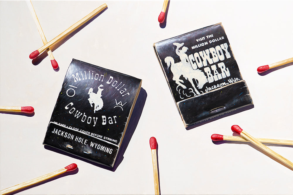 Painting of two matchboxes labeled ' Million Dollar Cowboy Bar' with matches scattered around on a light background.