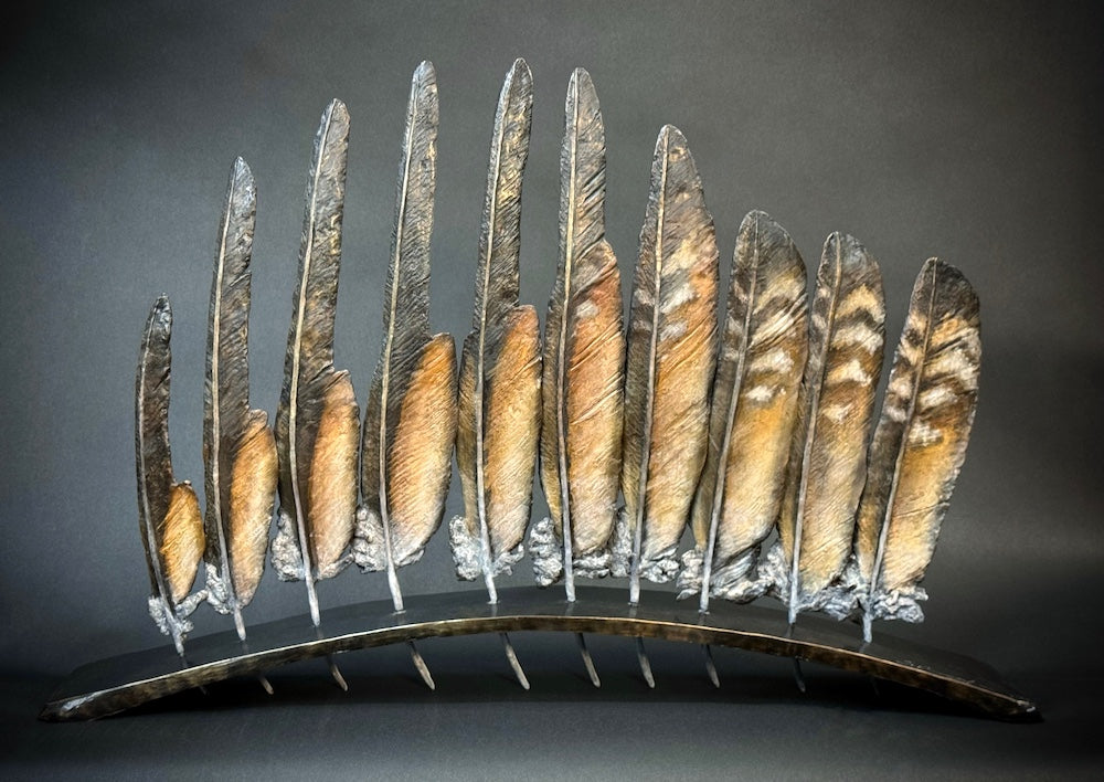 Bronze sculpture of feathers in a row by Stephanie Revennaugh